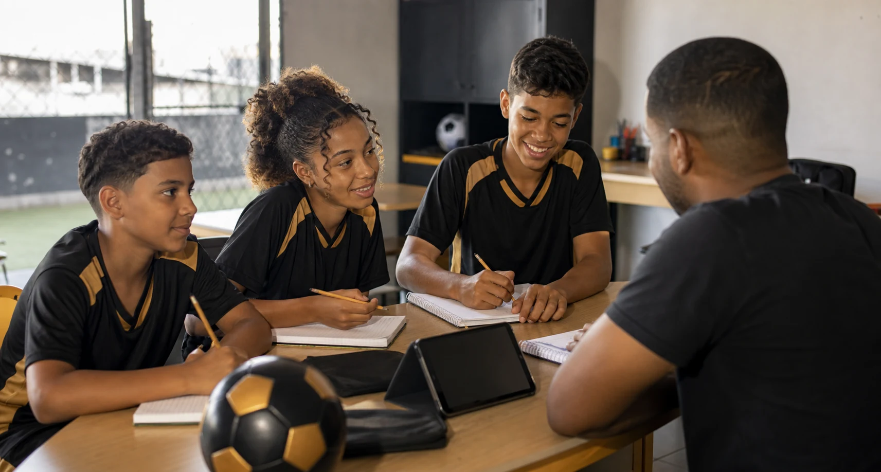 Jovens estudando com um mentor em sala de apoio educacional