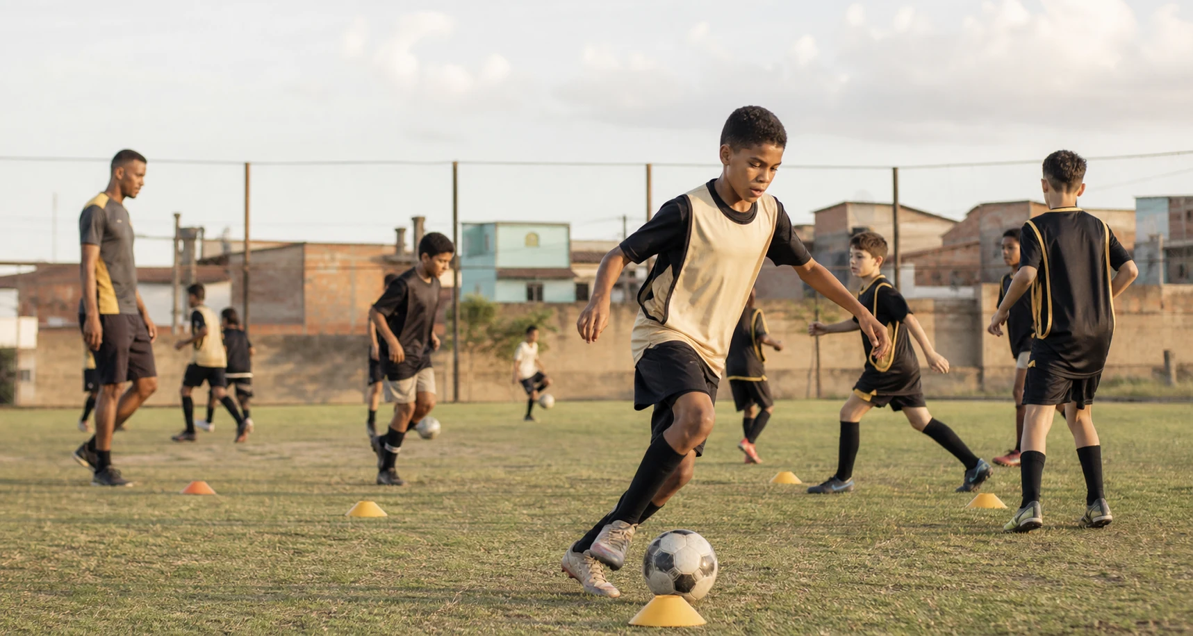 Crianças treinando futebol em campo comunitário